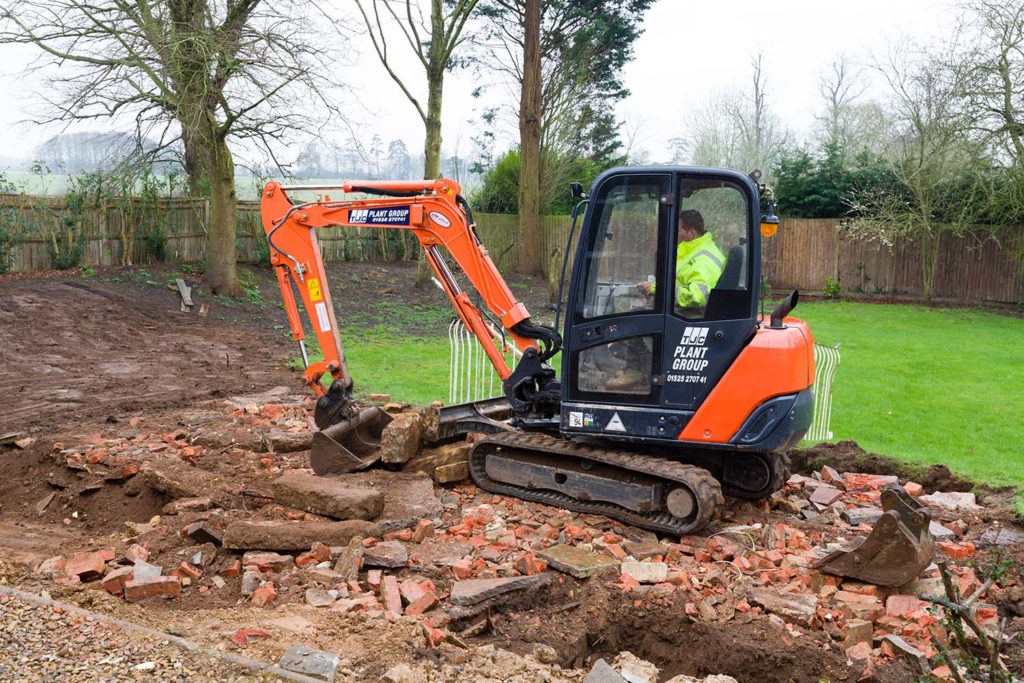 Digger, bulldozer clearing rubble in preparation for hard landscaping a garden in UK